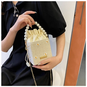 Detailed view of straw bucket bag with daisy embroidery and elegant pearl handle
