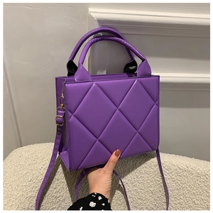 Detailed close-up of quilted purple PU leather handbag with golden hardware and top handles