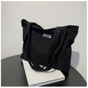 Détail du sac fourre-tout en velours côtelé noir avec rayures et étiquette de mode