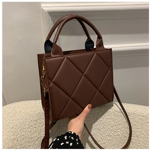 Detailed macro view of deep brown quilted faux leather handbag with golden metal hardware