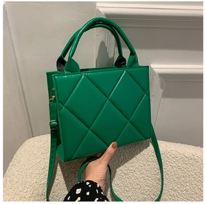 Detail of lime green quilted small square bag with polished finish and top handle