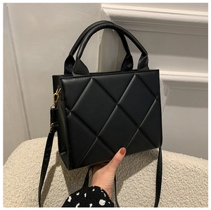 Detail of black quilted shoulder bag featuring gold metal hardware and stitching