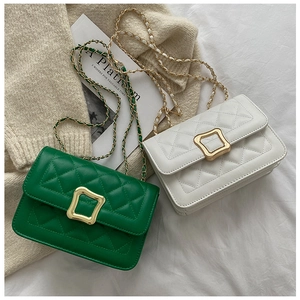 Close-up of quilted chain bags in green and white with gold square buckles and texture