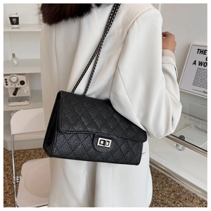 Detail of black quilted leather shoulder bag with metallic buckle and chain strap