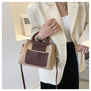 Detail of contrast leather handbag with wooden round handle and metallic rivets
