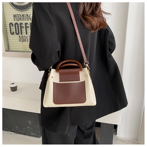 Chic two-tone shoulder bag with wooden handles styled with a black blazer in a cafe