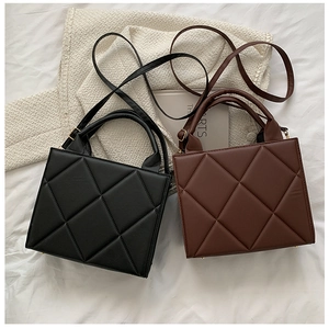 Close-up of quilted square handbags in black and brown with elegant gold hardware detail
