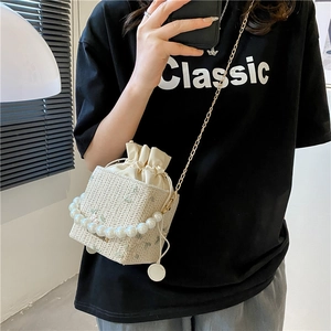 Beige woven straw crossbody bag with pearl handle and metal chain for summer style