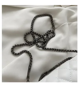 Detail of elegant gunmetal box chain strap on quilted white leather crossbody bag
