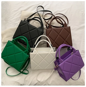 Top view of five colorful quilted crossbody bags arranged on a soft white fabric surface