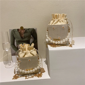 Woven straw bucket bags with daisy embroidery, pearl handles and gold chain straps