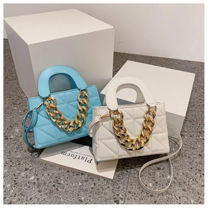 Close-up of quilted PU leather flap handbags with chunky gold chain straps in blue and white