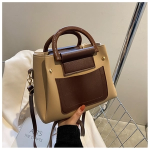 Detail of a chic apricot and dark brown patchwork square bag with a glossy arched handle