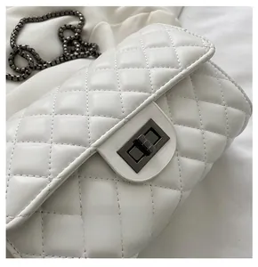 Close-up of white quilted leather texture and metallic rectangular twist lock on bag