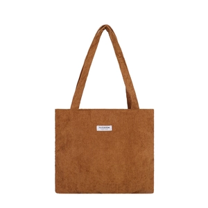 Sac fourre-tout en velours côtelé marron avec écusson blanc et deux bretelles sur fond blanc