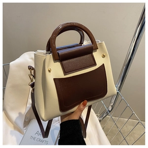 Detail of vintage beige and brown shoulder bag with rounded handle and gold hardware