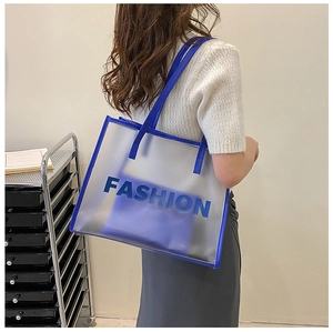 Detailed view of the clear PVC tote bag with Klein blue trim on a model shoulder
