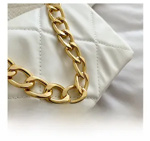 Détail du cuir matelassé blanc et de la poignée en chaîne dorée sur le petit sac carré