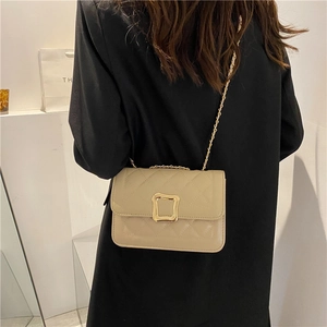 Chic quilted beige crossbody bag with gold square buckle and chain strap on shoulder