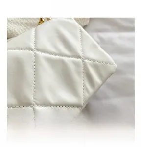 Détail macro de la texture du cuir matelassé blanc et de la chaîne dorée du sac