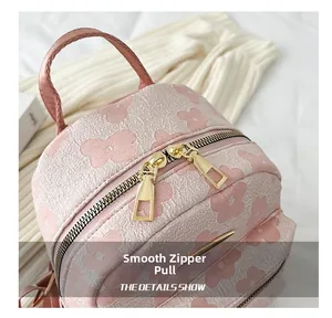 Gros plan des doubles fermetures éclair dorées sur un petit sac à dos à fleurs rose
