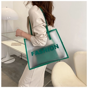 Detail of transparent jelly tote bag with green FASHION print and matching inner pouch