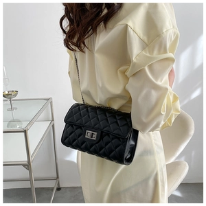 Detail of black quilted leather texture and silver turn-lock clasp on the crossbody bag