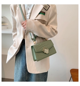 Detail view of mint green crocodile-embossed bag featuring a golden diamond buckle