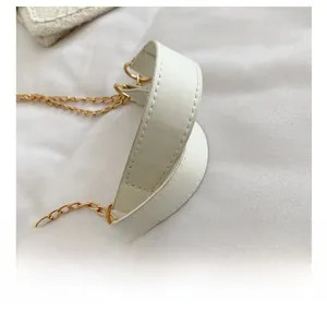 Détail de la poignée en similicuir blanc avec coutures fines et chaîne dorée du sac