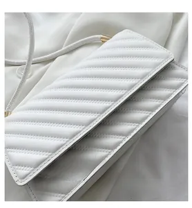Detailed macro view of white quilted leather texture and golden metal bag hardware
