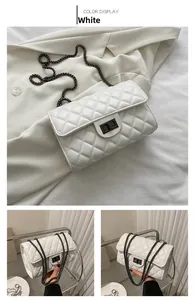 Detail view of a white quilted crossbody bag with metal chain strap and turn-lock