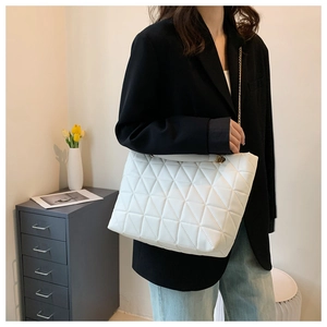 Détail d'un sac à main blanc matelassé avec motif triangle et bandoulière en chaîne