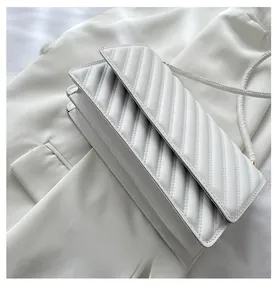 Detail view of multi-layered ivory baguette bag with elegant V-shaped quilting pattern