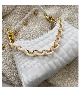 Detailed view of white embossed leather handbag with chunky resin and gold metal chain