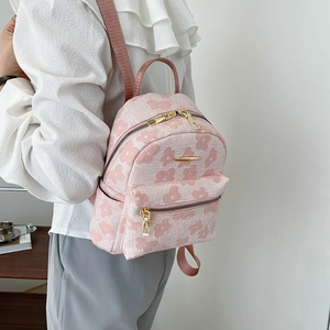 Détail d'un mini sac à dos en toile rose fleuri avec fermetures éclair dorées et poches
