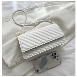 Detailed comparison of white quilted flap bag size relative to a smartphone