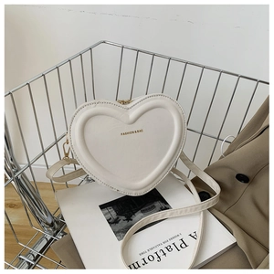 Détail d'un sac à bandoulière beige en cuir PU en forme de cœur dans un panier en métal