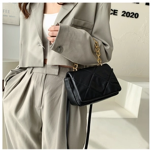 Détail du sac bandoulière matelassé noir avec chaîne dorée et texture en cuir mat raffiné