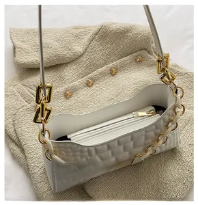 Close-up of woven white shoulder bag with gold chain strap and interior zipper pocket