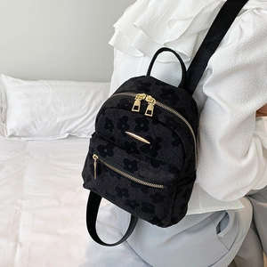 Détail d'un sac à dos en velours à motif floral noir avec fermetures éclair dorées