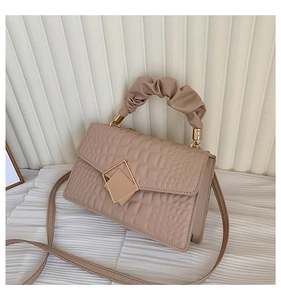 Close-up of beige crocodile pattern handbag with pleated handle and gold clasp