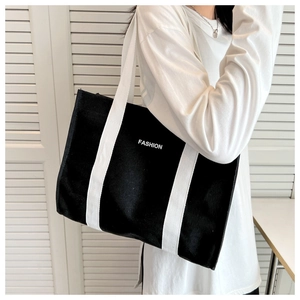 Detailed macro view of black canvas tote bag featuring white FASHION lettering text