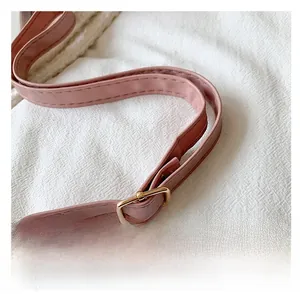 Detail of light pink leather adjustable shoulder strap with gold-tone metal buckle