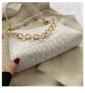 Detailed view of white crocodile texture underarm bag with thick gold chain accessory