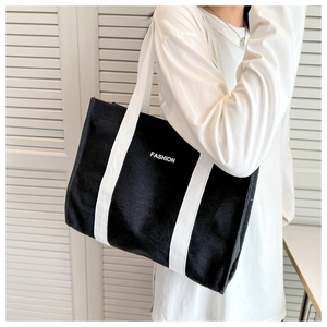 Detail of black canvas tote bag showing white FASHION print and sturdy strap texture