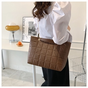 Détail d'un sac cabas marron café matelassé avec bandoulière chaîne dorée sur mannequin