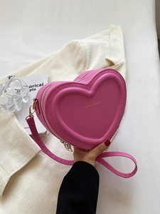 Gros plan du sac à main en forme de cœur en cuir PU rouge rose avec détails dorés