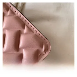 Macro detail of pink faux leather bag with embossed weave texture and precise stitching