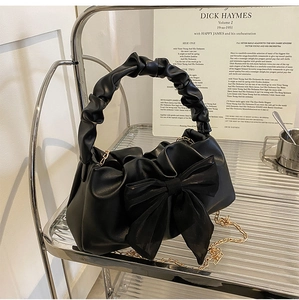 Detail of black bow handbag featuring cloud pleated handle and elegant gold chain strap