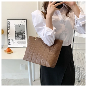 Détail du cabas matelassé marron avec texture cuir raffinée et bandoulière en chaîne dorée